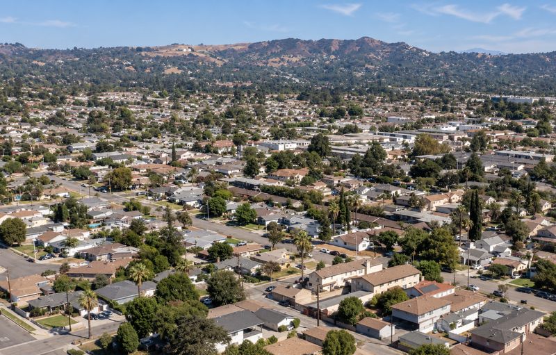 Aerial view of Covina, California, showing residential neighborhoods, tree-lined streets, and rolling hills in the distance.